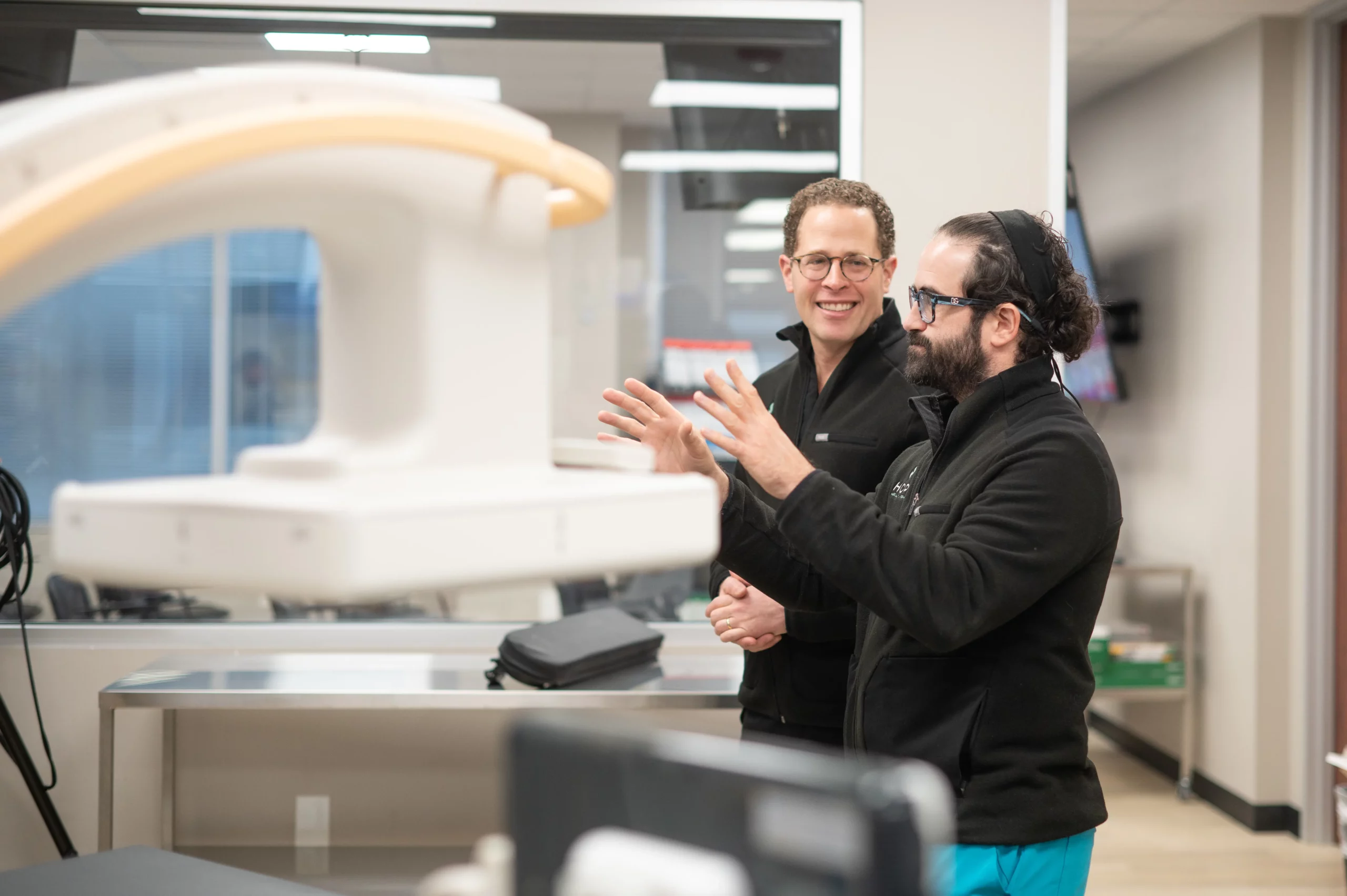 Two healthcare professionals discussing medical imaging equipment in a clinical room.